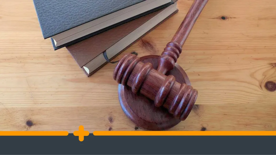Drewniany młotek sędziowski i książki prawnicze na biurku