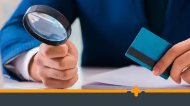 Mężczyzna w garniturze trzymający lupę i kartę kredytową