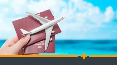 Dłoń trzymająca paszporty i model samolotu na tle morza, symbolizująca podróż lub wakacyjny wyjazd.